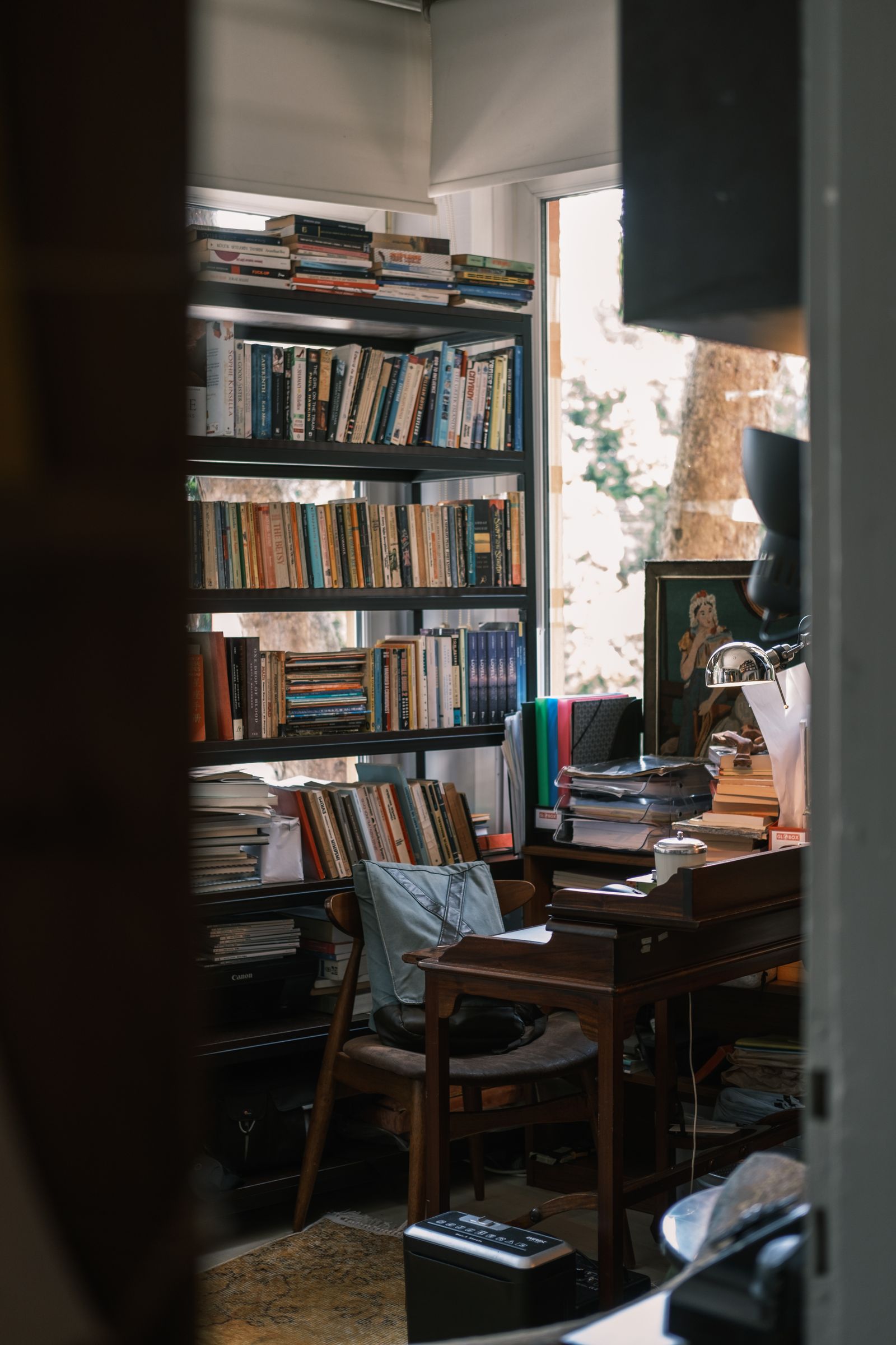 A wooden writing desk surrounded by bookshelves in a warm library